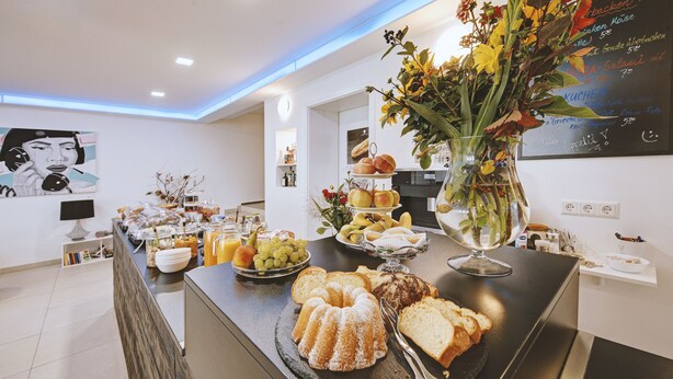 A buffet table with various food items and a decorative vase. - Boutique-Hotel Kronenstuben (Ludwigsburg)
