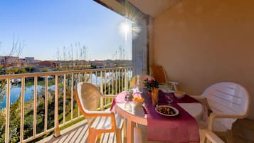 A balcony with a table set for two, overlooking a body of water and buildings.