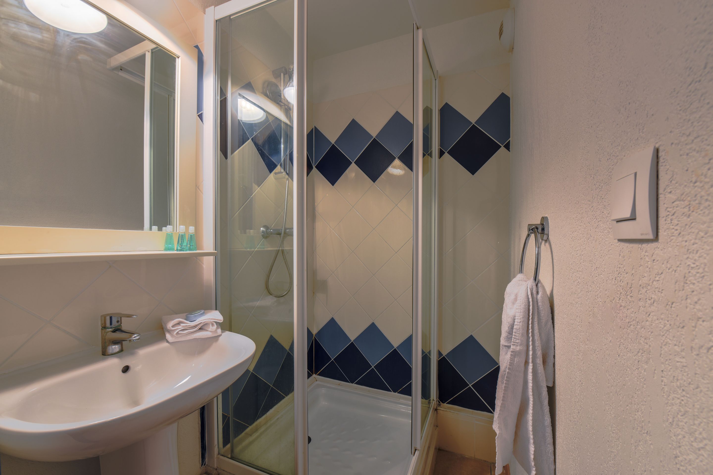 A bathroom with a sink, mirror, and shower.