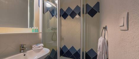 A bathroom with a sink, mirror, and shower.
