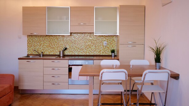 Une cuisine moderne avec des meubles en bois, un pare-feu en carreaux et un coin repas comprenant une table et des chaises.