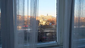 Une vue à travers une fenêtre avec des rideaux, donnant sur un paysage urbain avec des bâtiments et une rivière.