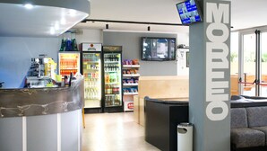 Un restaurant doté d’un comptoir, d’un espace pour s’asseoir et d’un grand écran diffusant du contenu.