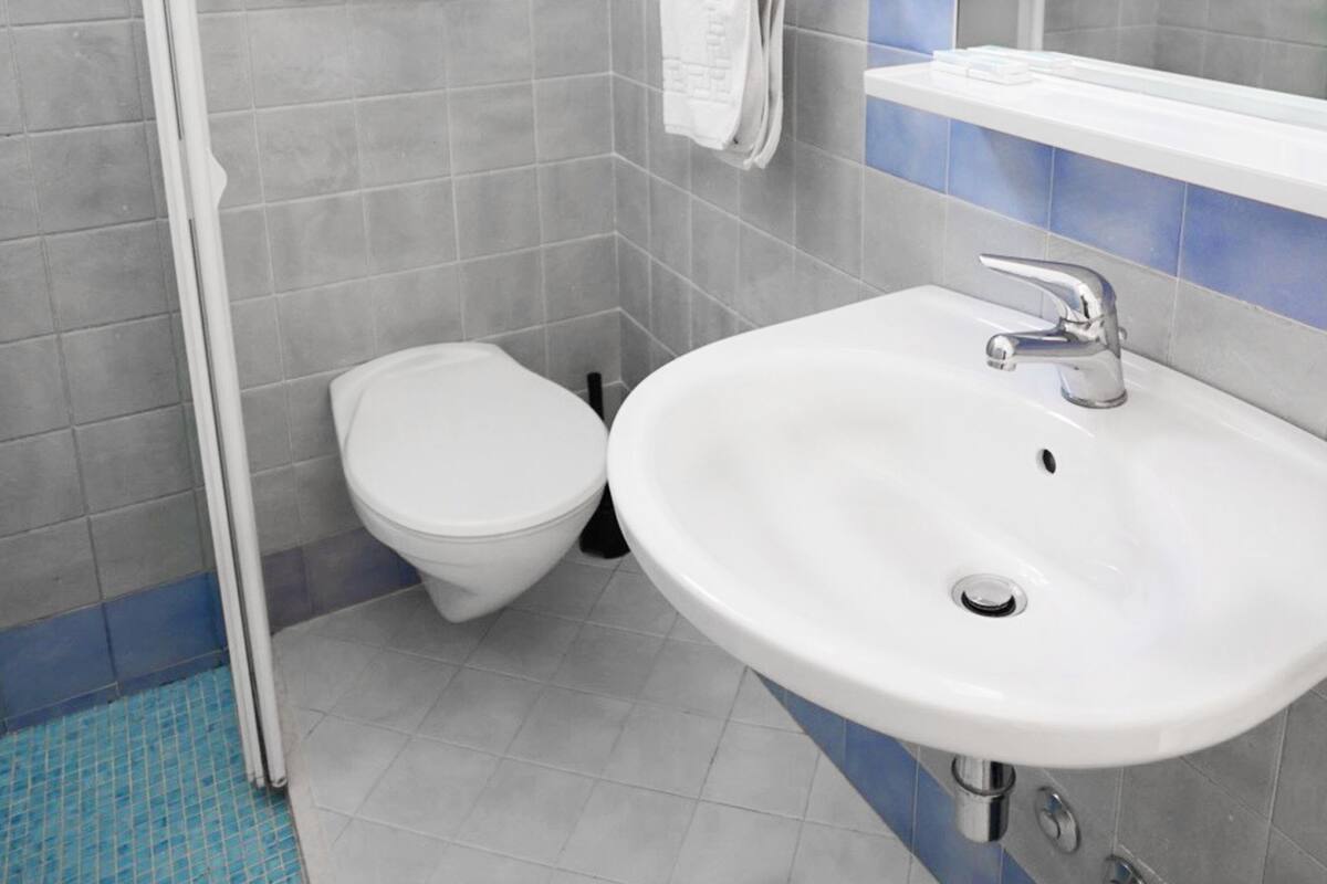 Een badkamer met een wit toilet, een witte wastafel en een spiegel boven de wastafel.