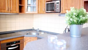 A modern kitchen with wooden cabinets, a stainless steel sink, a microwave, and a dishwasher.