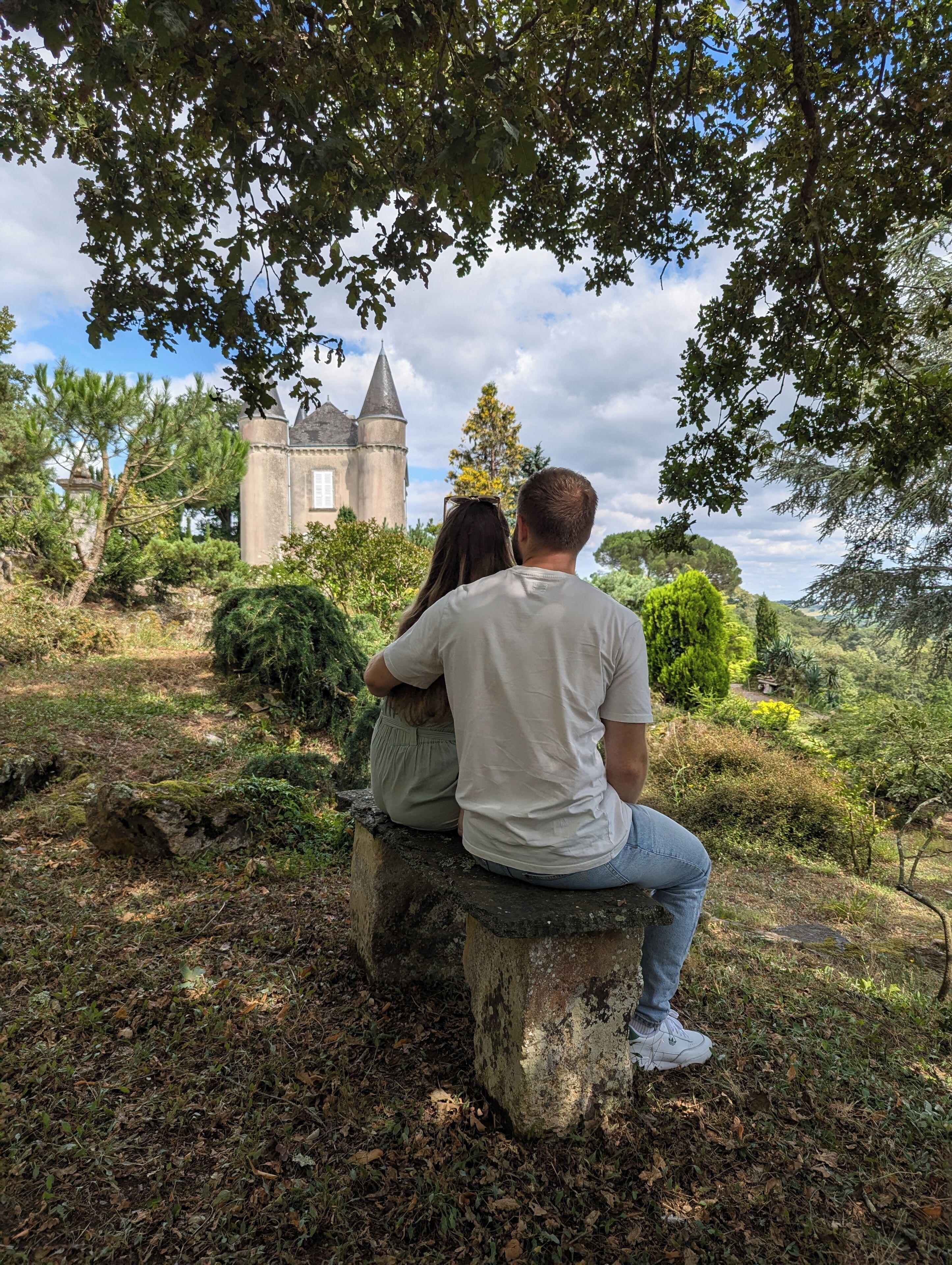 A couple sitting on a stone bench overlooking a castle.