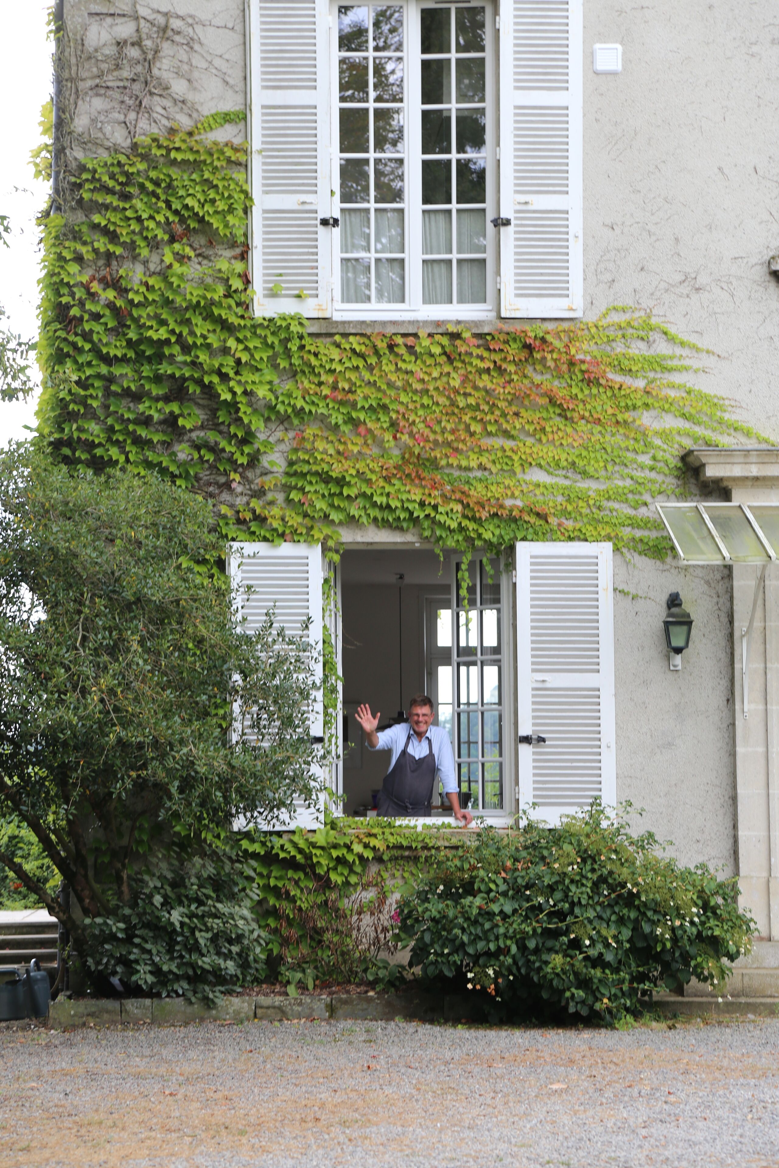 Un bâtiment doté d’une fenêtre et d’une porte, entouré de verdure.