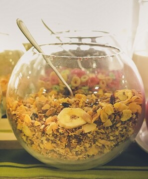 A bowl of granola with dried fruits and a spoon. - Nuevo Hotel (Rivera)