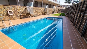 Une piscine avec un mur en pierre et une clôture en métal.