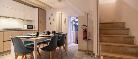 A modern kitchen with a dining area, featuring a staircase and a fire extinguisher.