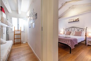 A room with a bunk bed, a wooden ladder, a radiator, and a wall with framed pictures.
