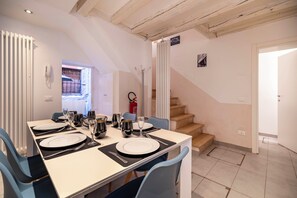 Un comedor con una mesa dispuesta para cuatro, una escalera y una puerta que da a un espacio exterior.