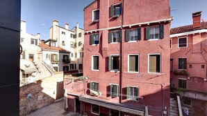 A red building with multiple windows and balconies, a visible staircase, and a narrow street. - San Marco Prestige - S Zaccaria by Wonderful Italy (Venice)