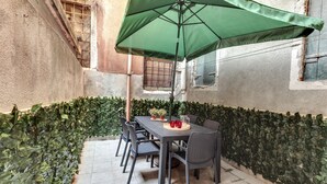An outdoor patio with a table and chairs under a green umbrella, surrounded by a hedge. - San Marco Prestige - S Zaccaria by Wonderful Italy (Venice)
