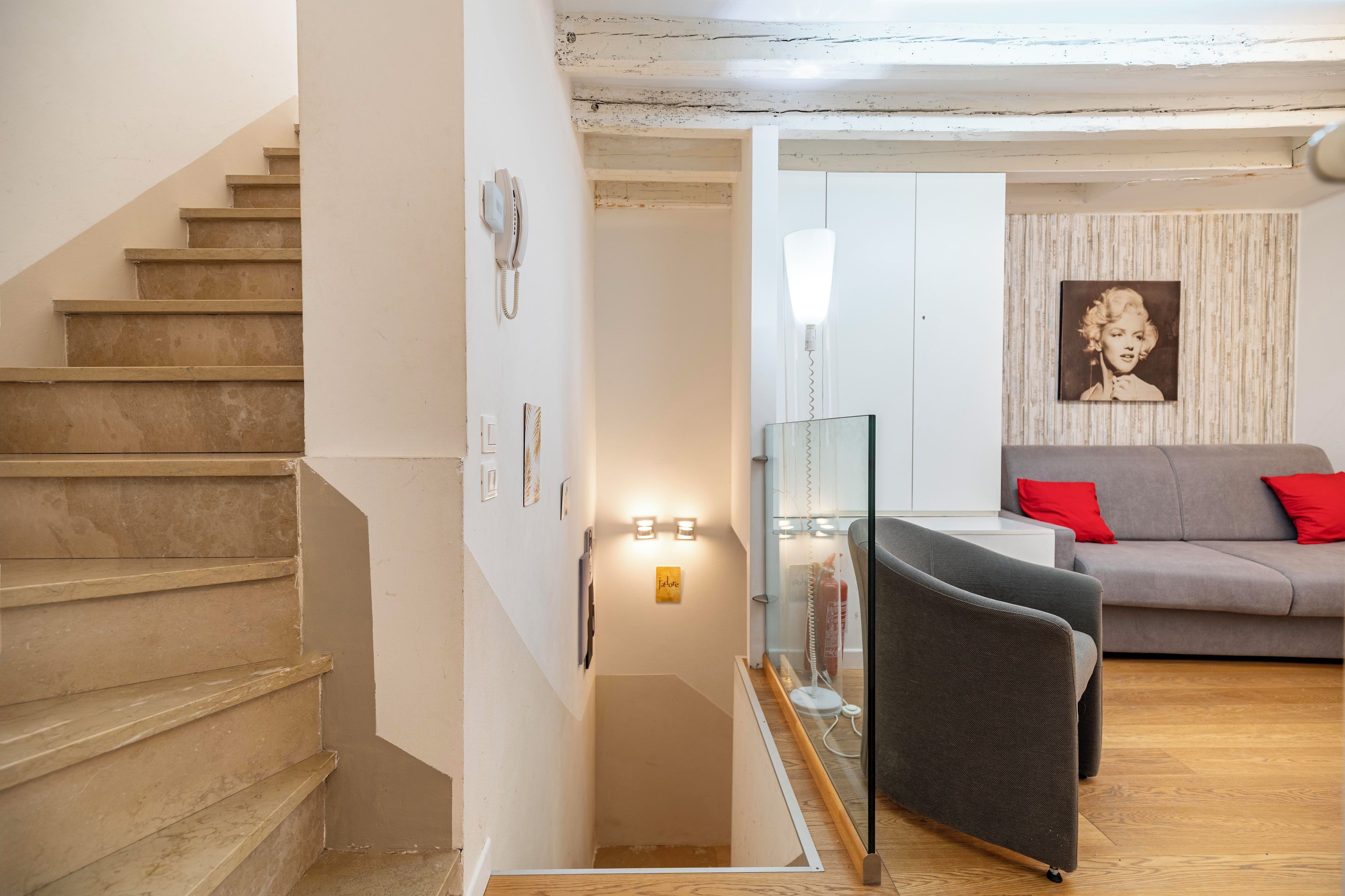 Una escalera que conduce a una sala de estar con un sofá y un separador de vidrio.