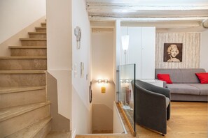 Una escalera que conduce a una sala de estar con un sofá y un separador de vidrio.