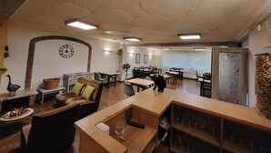 Un hall amplio con un diseño moderno de techo, un reloj y una zona de estar con sofá y sillas.