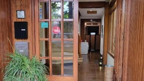 Una puerta de madera con un panel de vidrio, una planta en maceta, un buzón y un felpudo en la entrada.