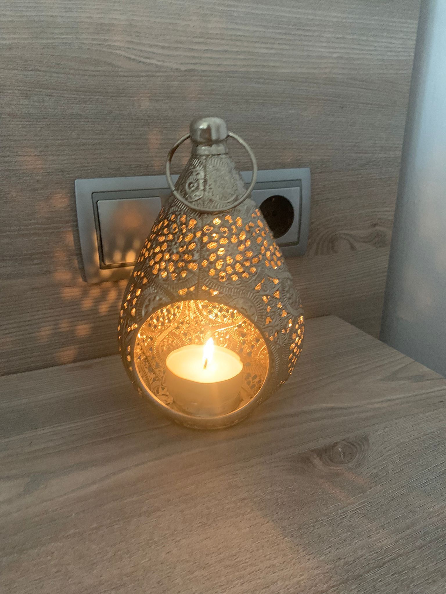 Una vela dentro de un farol decorativo sobre una superficie de madera.