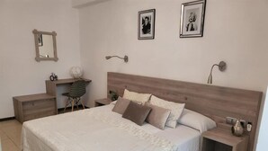 Un dormitorio con una cama grande, cabecera de madera, mesitas de noche, un espejo y cuadros enmarcados en la pared.