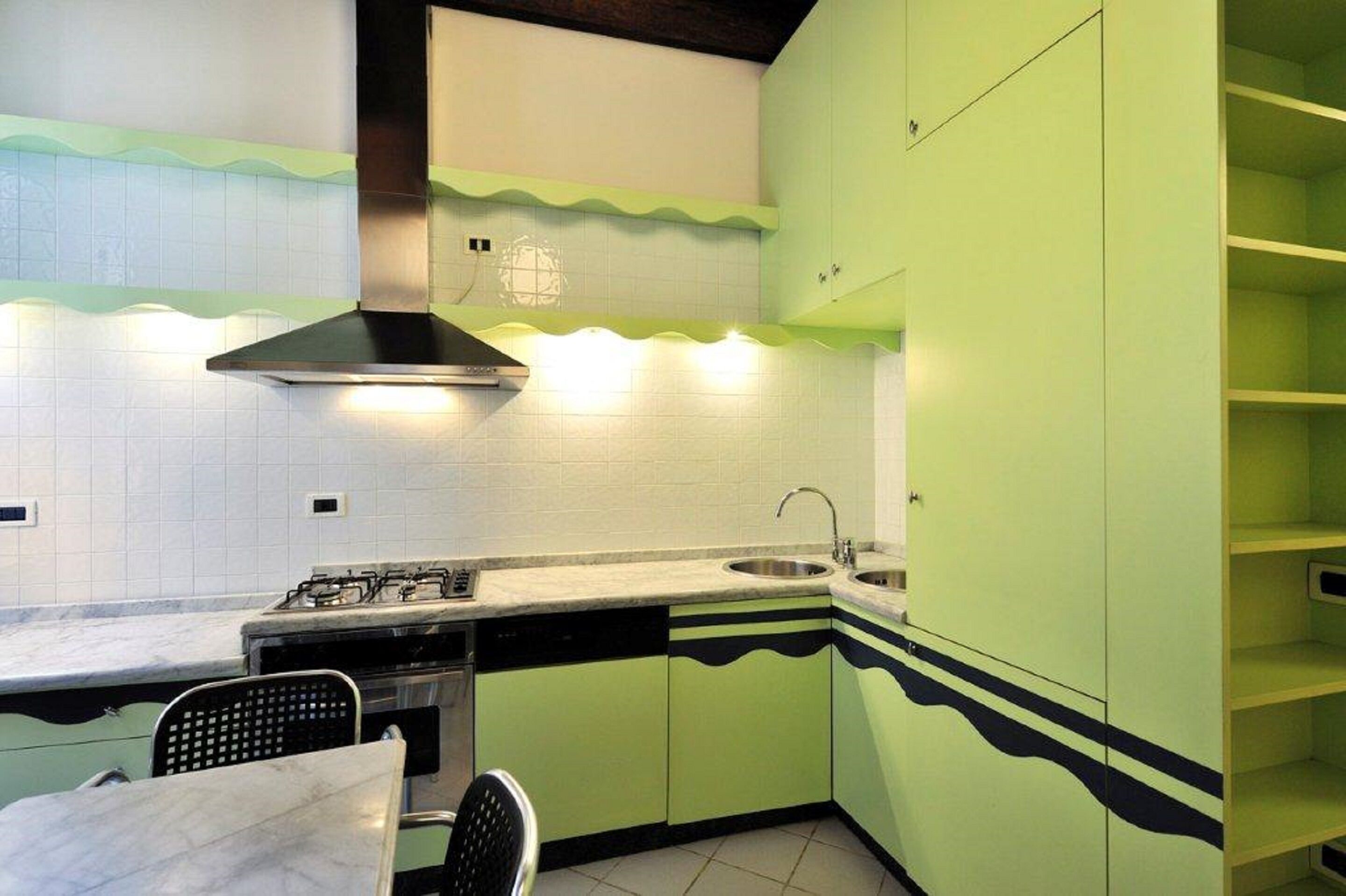 A compact kitchen with a gas stove, sink, and green cabinets.