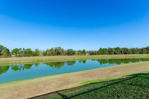 A tranquil outdoor scene with a clear blue sky, a calm water body, and a grassy area. - 8417 SKC (Kissimmee)