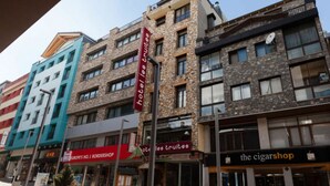 Un immeuble à plusieurs étages dont le rez-de-chaussée abrite divers commerces, notamment une boutique de tabac et un magasin de cigares.