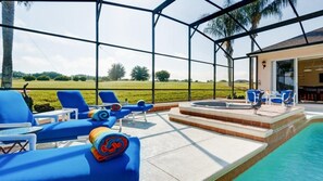 A poolside area with blue lounge chairs, a hot tub, and a view of a green field. - 354PD (Davenport)
