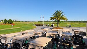 A golf course with a parking area, flags, and a palm tree. - Providence at Victoria Woods -2389GVDJGIL (Davenport)