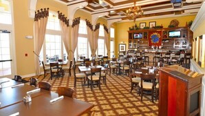 A hotel lobby with a bar area, multiple dining tables, and a patterned carpet. - Providence at Victoria Woods -2389GVDJGIL (Davenport)