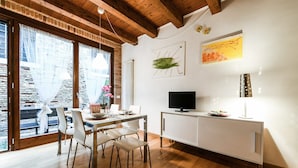 Ein Essbereich mit einem Holztisch, weißen Stühlen und einem weißen Schrank mit einem Fernseher.