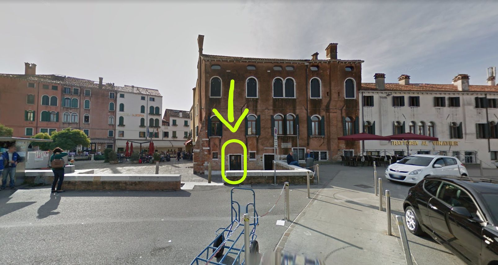 A street view with a building featuring arched windows and a red awning.