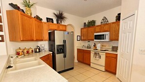 A kitchen with wooden cabinets, a stainless steel refrigerator, a microwave, an oven, and a sink. - 313 Glen (Davenport)