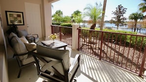 A balcony with a view of a lake, surrounded by palm trees and a fence. - Lake View Joy (Orlando)