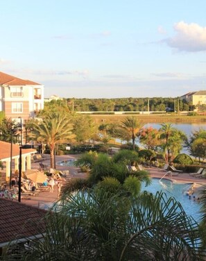A resort with a swimming pool surrounded by palm trees and lounge chairs. - Lake View Joy (Orlando)
