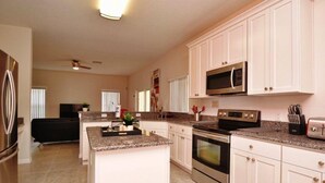 A modern kitchen with white cabinets, granite countertops, stainless steel appliances, and a central island. - 616BD (Davenport)
