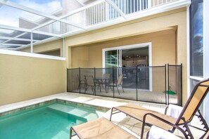 A pool area with lounge chairs and a glass-enclosed patio.