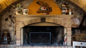 A stone fireplace with a brick arch, a decorative sign above it, and various items like a vase, a pitcher, and a plate on the mantel. - Al Regio Tratturo (Manoppello)
