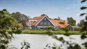 Ett hus med ett sluttande tak, en balkong och utsikt över en sjö eller ett annat vattendrag.