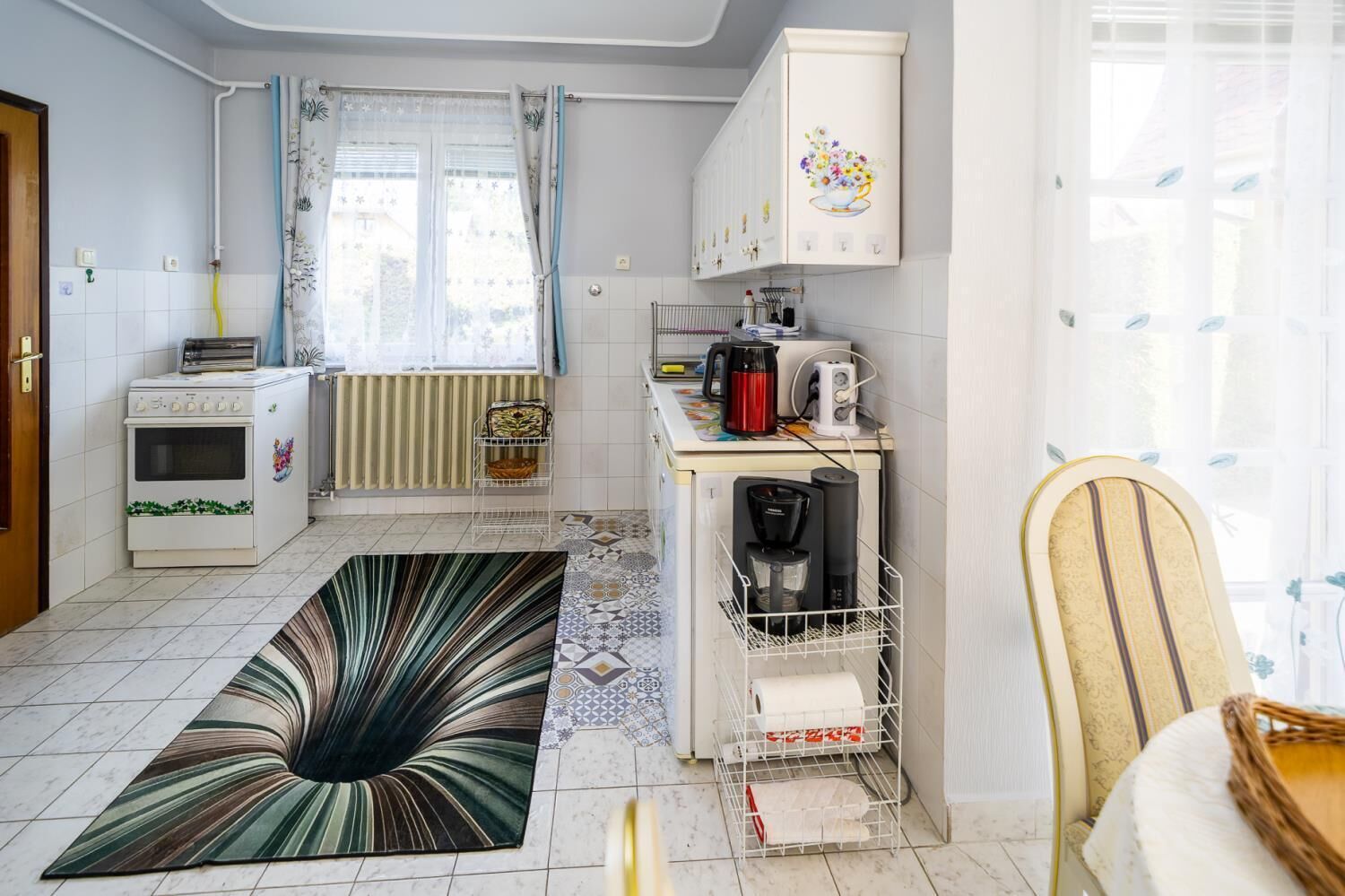 A compact kitchen with a built-in oven, a coffee maker, and a kettle on the counter.