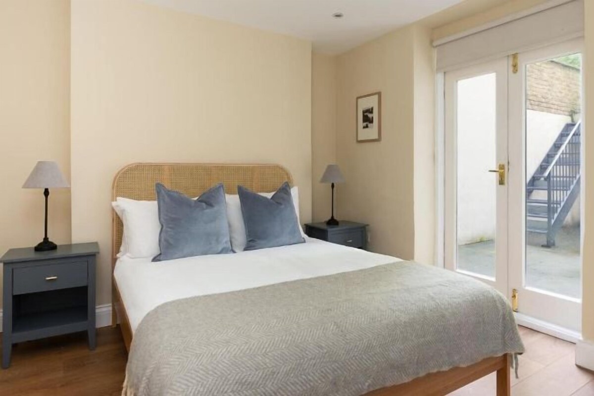 Een slaapkamer met een bed, twee nachtkastjes, een raam en een deur naar een buitenruimte.