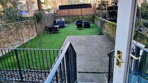 A view of a courtyard with a grassy area, outdoor seating, and a stone wall.