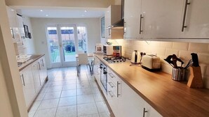 A modern kitchen with white cabinets, a wooden countertop, and a view to a patio area.