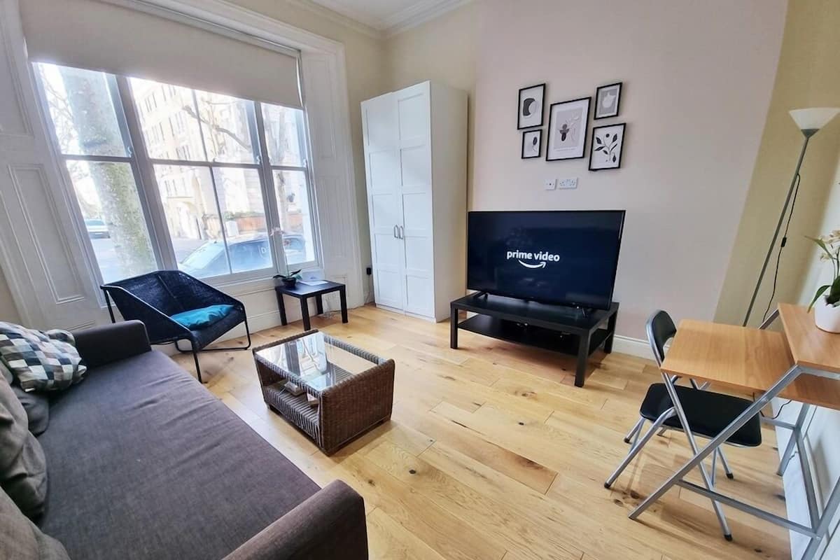 Una sala de estar moderna con un sofá, una mesa de centro de vidrio, un televisor y un comedor con una mesa y sillas.