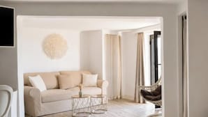 A modern hotel room with a sofa, a chair, a small table, and a bed. - L'Hostellerie Du Moulin Des Oliviers (Olmeto)