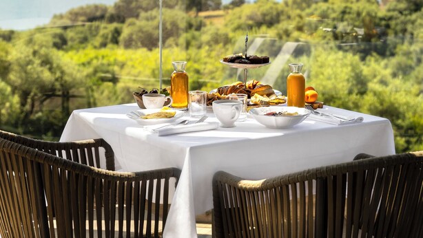 A table set for breakfast with a scenic view of mountains and a body of water. - L'Hostellerie Du Moulin Des Oliviers (Olmeto)