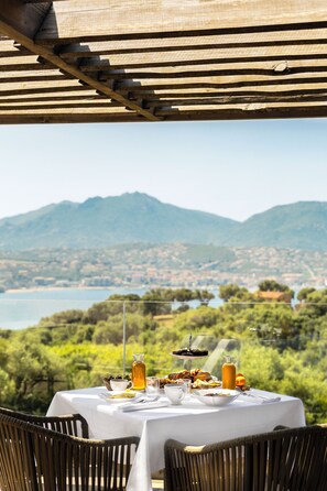 Una mesa lista para el desayuno con vistas panorámicas a montañas y un cuerpo de agua.