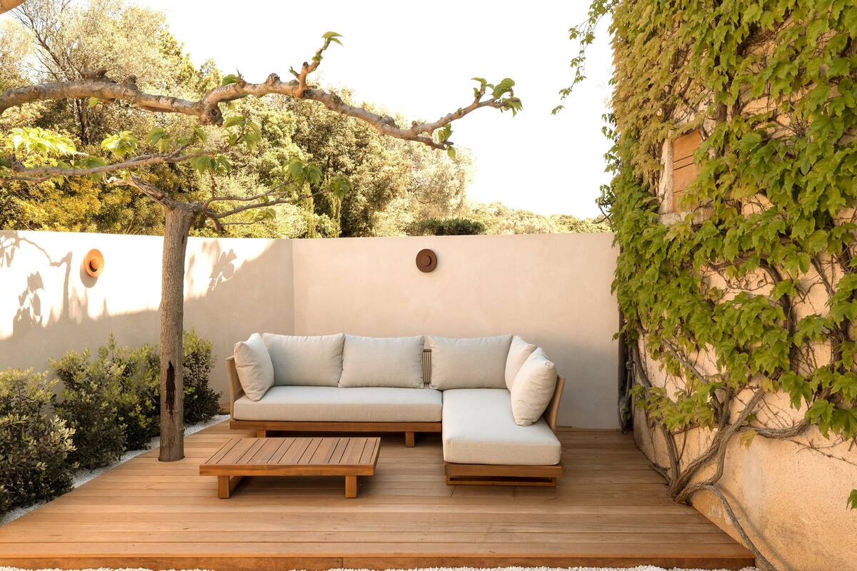 A wooden deck with a beige sectional sofa and a small table.
