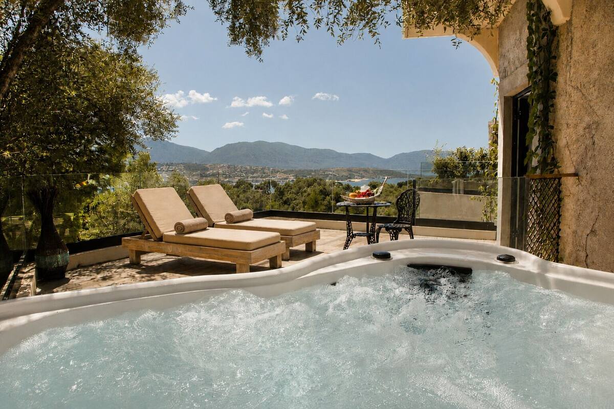 A hot tub with lounge chairs, a table with fruit, and a view of mountains.