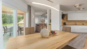 A modern kitchen with a wooden dining table, a vase with fruit, and a view of the outdoors. - Awesome home in Labin (Labin)
